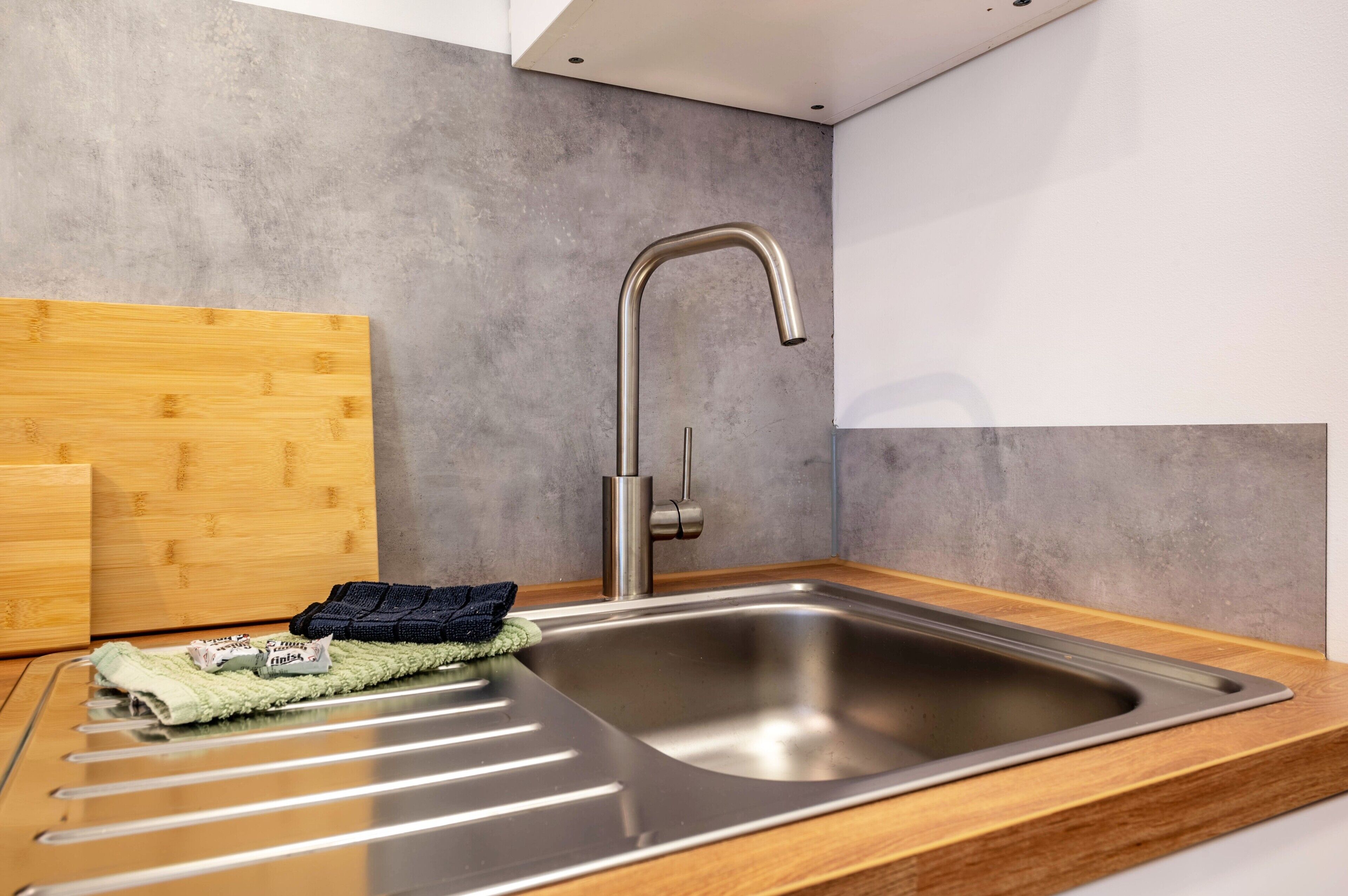 A modern kitchen with a stainless steel sink, wooden countertop, and a towel rack.