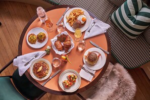 A round table with various breakfast items, including pancakes, eggs, and sandwiches, surrounded by chairs and a furry rug. - Belden House & Mews (Litchfield)