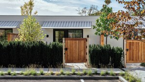 A modern house with a white exterior, two wooden doors, and a grey awning.