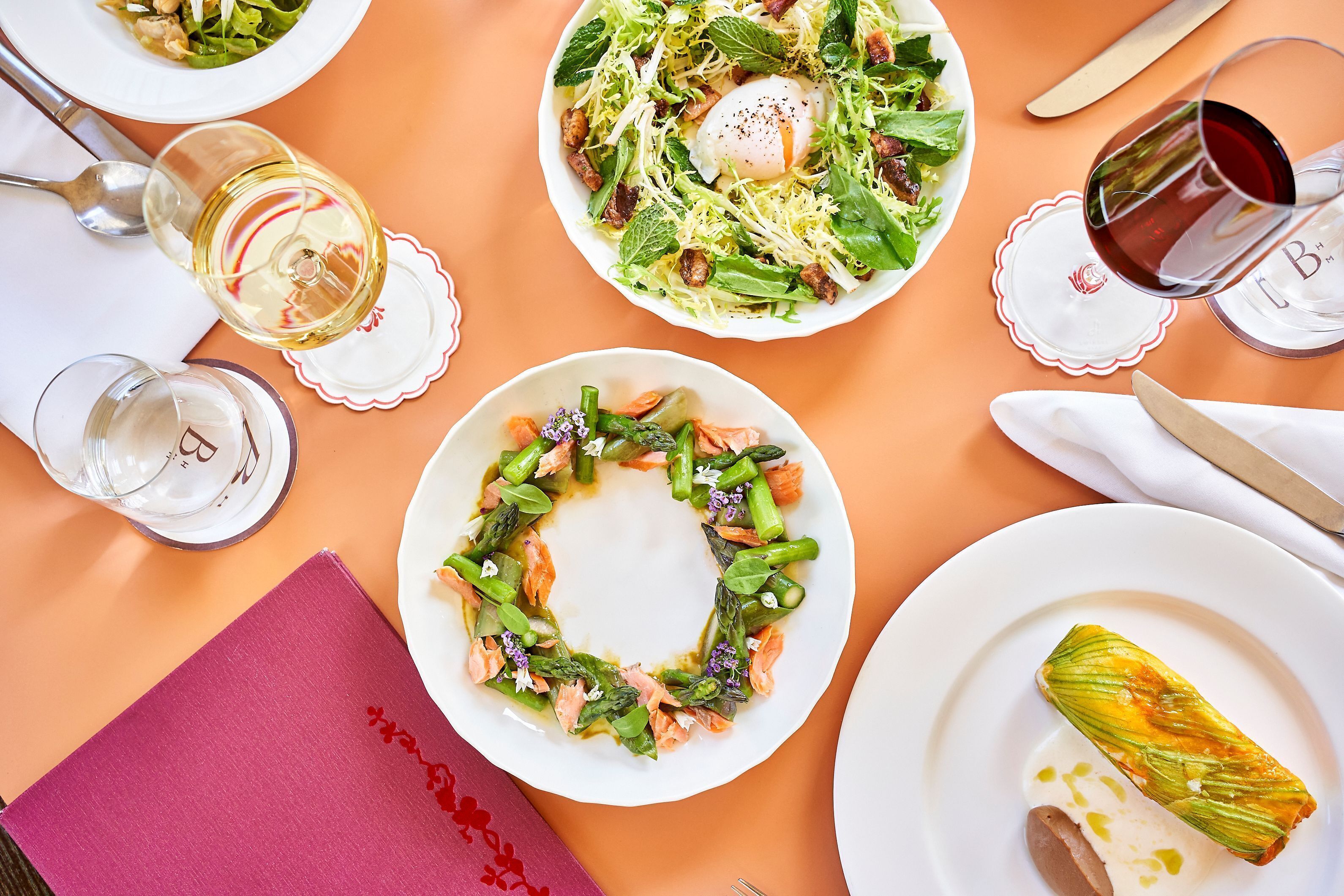 A table with plates of food, glasses of wine, and cutlery.