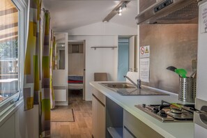 Uma cozinha compacta com pia, fogão e vista para o quarto vizinho.