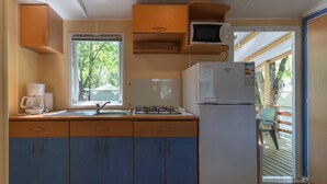 Una cucina compatta con lavandino, piano cottura, microonde e frigorifero.