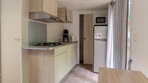 A compact kitchen with a gas stove, microwave, and a coffee maker. - Mobile Home 'Confort B - 1-6 Pers' with Shared Pool, Private Terrace and Shared Garden (Lavilledieu)