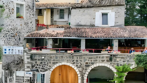 A pool area with lounge chairs, a stone archway, and a building with a terrace. - Mobile Home 'Confort B - 1-6 Pers' with Shared Pool, Private Terrace and Shared Garden (Lavilledieu)