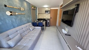 Ein gemütlicher Wohnbereich mit Sofa, Essbereich mit Stühlen, einer Küche mit Mikrowelle und einem an der Wand montierten Fernseher.