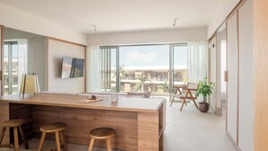 A modern kitchen with a wooden countertop, two stools, a large window, and a view of the outside. - KORA TIGOT (San Miguel de Abona)