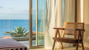 A room with a view of the ocean, a wicker chair, and a striped ottoman. - KORA TIGOT (San Miguel de Abona)
