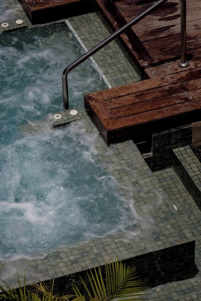 A hot tub with a wooden deck and metal railings.