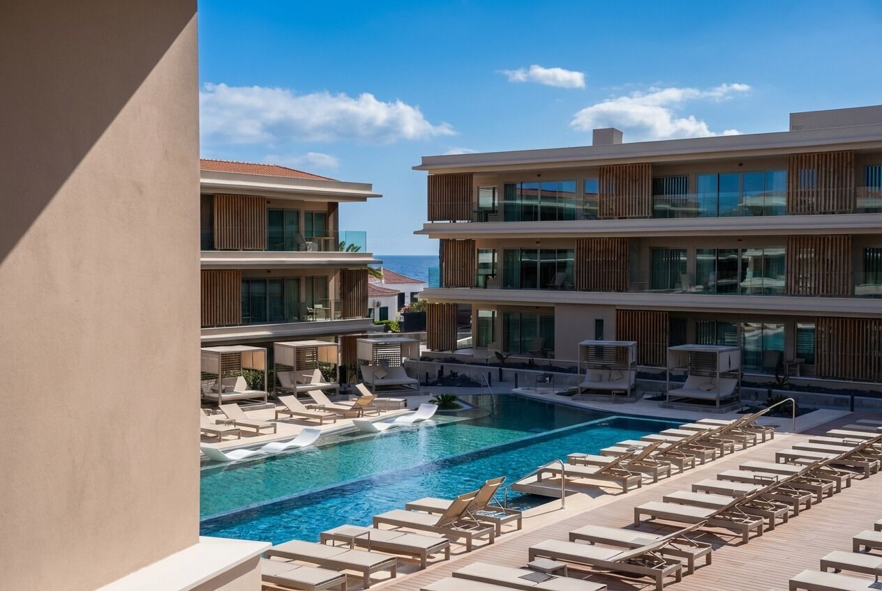 Un hotel moderno con piscina en la azotea, varios balcones y zonas de estar.
