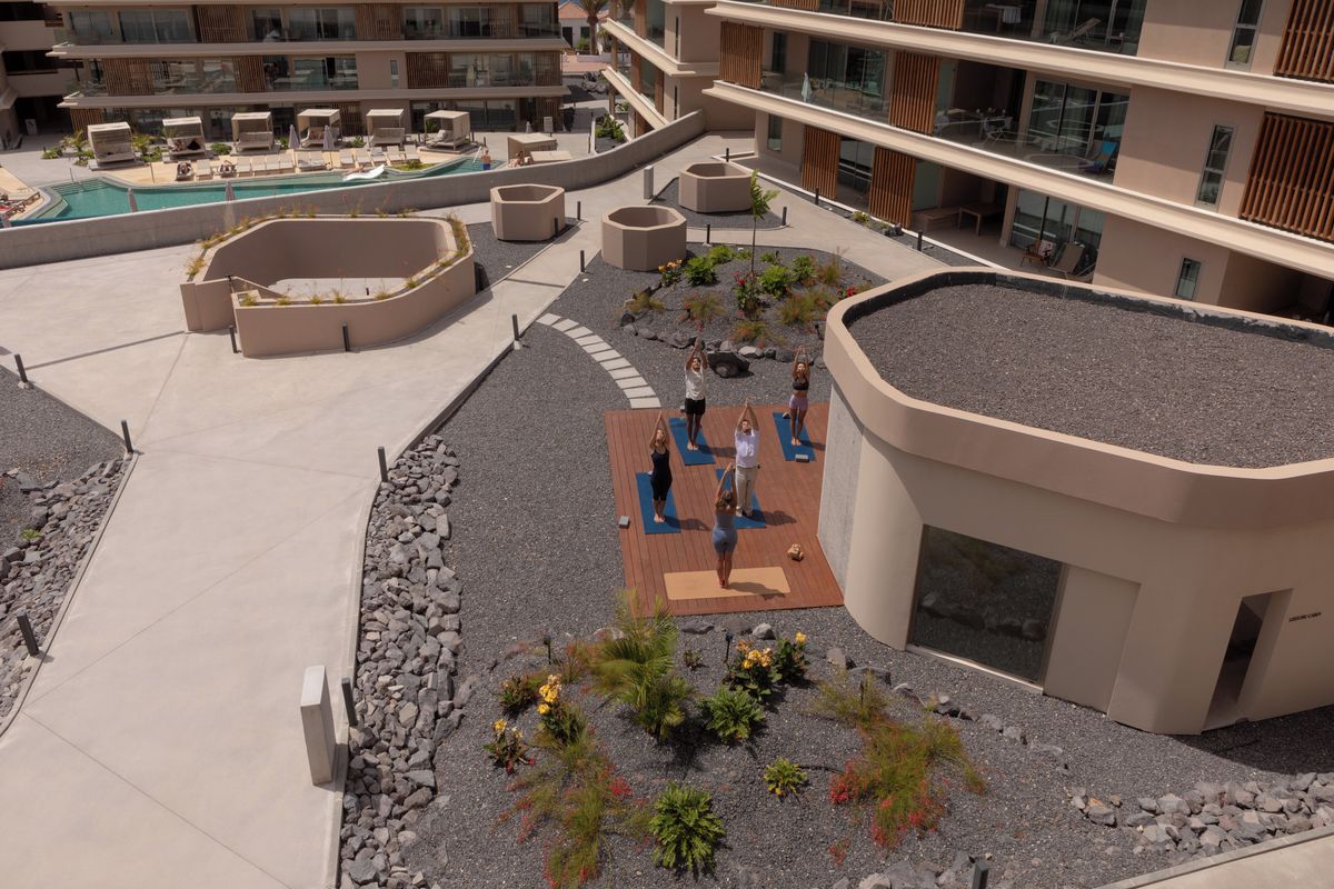 Un espacio en la azotea con un área para yoga, una piscina y un jardín ajardinado.