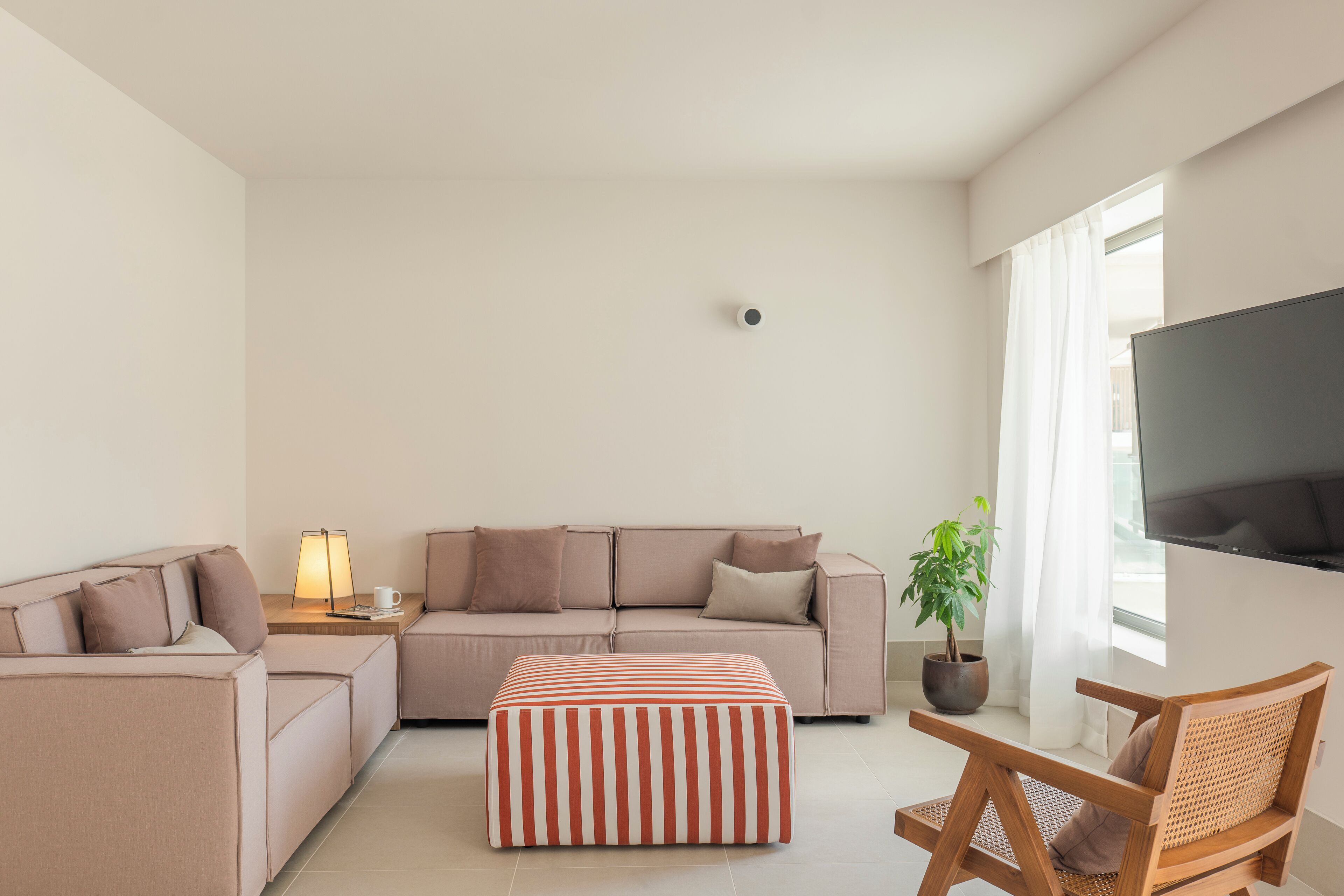 Un salon moderne avec un canapé, un pouf et une chaise en bois.