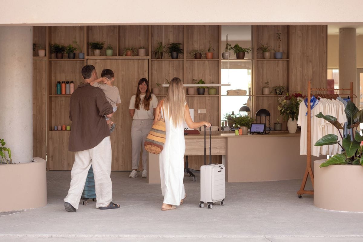 Un espace d’accueil comprenant un comptoir de réception en bois, un coin salon et une présentation de plantes.
