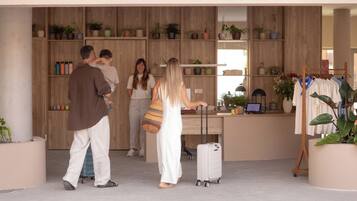Un espace d’accueil comprenant un comptoir de réception en bois, un coin salon et une présentation de plantes.