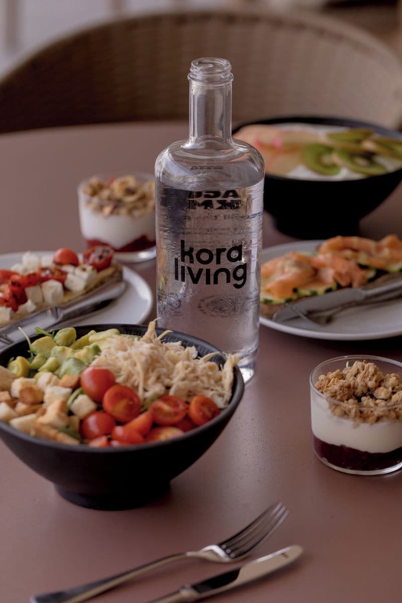 A dining table with various dishes, a bottle labeled 'kord living,' and cutlery.