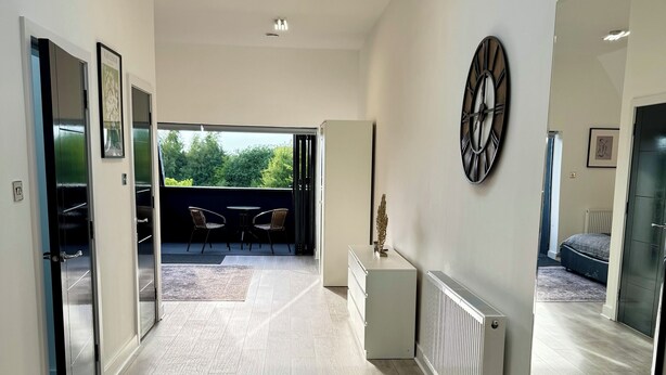 A spacious hallway with a skylight, a large mirror, and a view to an outdoor seating area. - Luxurious New House Near Manchester Airport (Wythenshawe)