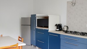 Una cocina moderna con armarios azules, una encimera blanca, una estufa y una mesa de comedor con sillas.