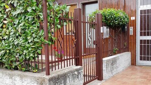 Edificio residencial con entrada protegida por un portón, un balcón y una puerta con el número 6.