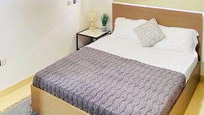 A bedroom with a bed, a nightstand, a lamp, and an air conditioner on the wall.