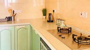 A kitchen with green cabinets, a stainless steel countertop, a gas stove, and a dishwasher.