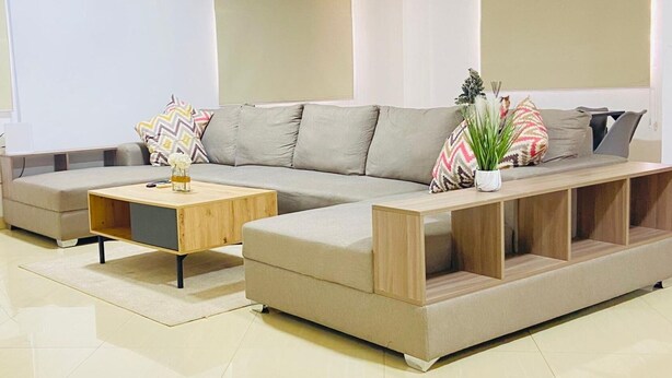 A modern living room with a sectional sofa, a wooden coffee table, and a potted plant.