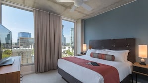 A hotel room with a large bed, a desk, and a view of the cityscape. - Beautiful 2 Bedroom Suite in Downtown Austin! (Austin)