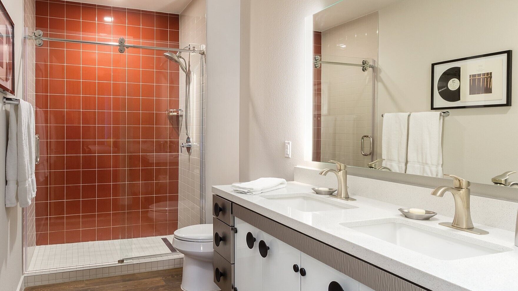 A modern bathroom with a shower, toilet, and vanity with a sink and mirror.