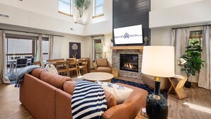 Una sala de estar amplia con chimenea, un comedor y un ventanal con cortinas.