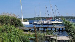 Un puerto deportivo con varios veleros amarrados, rodeado de agua y vegetación.