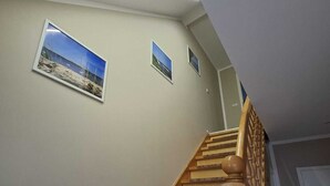 Una escalera de madera con barandilla, que lleva a un rellano con una puerta.