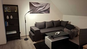 Una sala de estar moderna con un sofá modular, una mesa de centro, una lámpara de pie, una estantería y una obra de arte abstracto colgada en la pared.