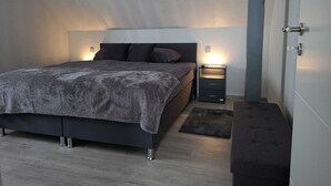 Un dormitorio moderno con cama, mesitas de noche y un banco.
