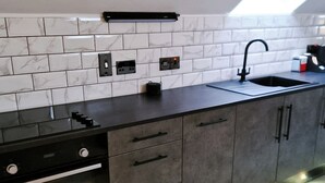 A modern kitchen with a built-in oven, a sink, and under-cabinet lighting. - Lorraine's Loft - Hot Tub Get Away. Stunning countryside Views! (Cookstown)