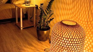 A cozy room with a wooden floor, a small table with a lamp, a potted plant, and a decorative lantern. - Lorraine's Loft - Hot Tub Get Away. Stunning countryside Views! (Cookstown)