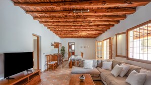 Un salon avec une télévision, un plafond en bois et un canapé.