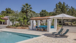 Une piscine avec des chaises longues et un espace salon abrité.