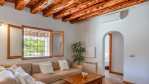 Un salon avec un canapé, une table basse en bois, une plante en pot et une fenêtre donnant sur un beau paysage.