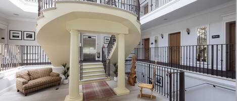 A spacious interior with a central staircase, a sofa, and a potted plant.