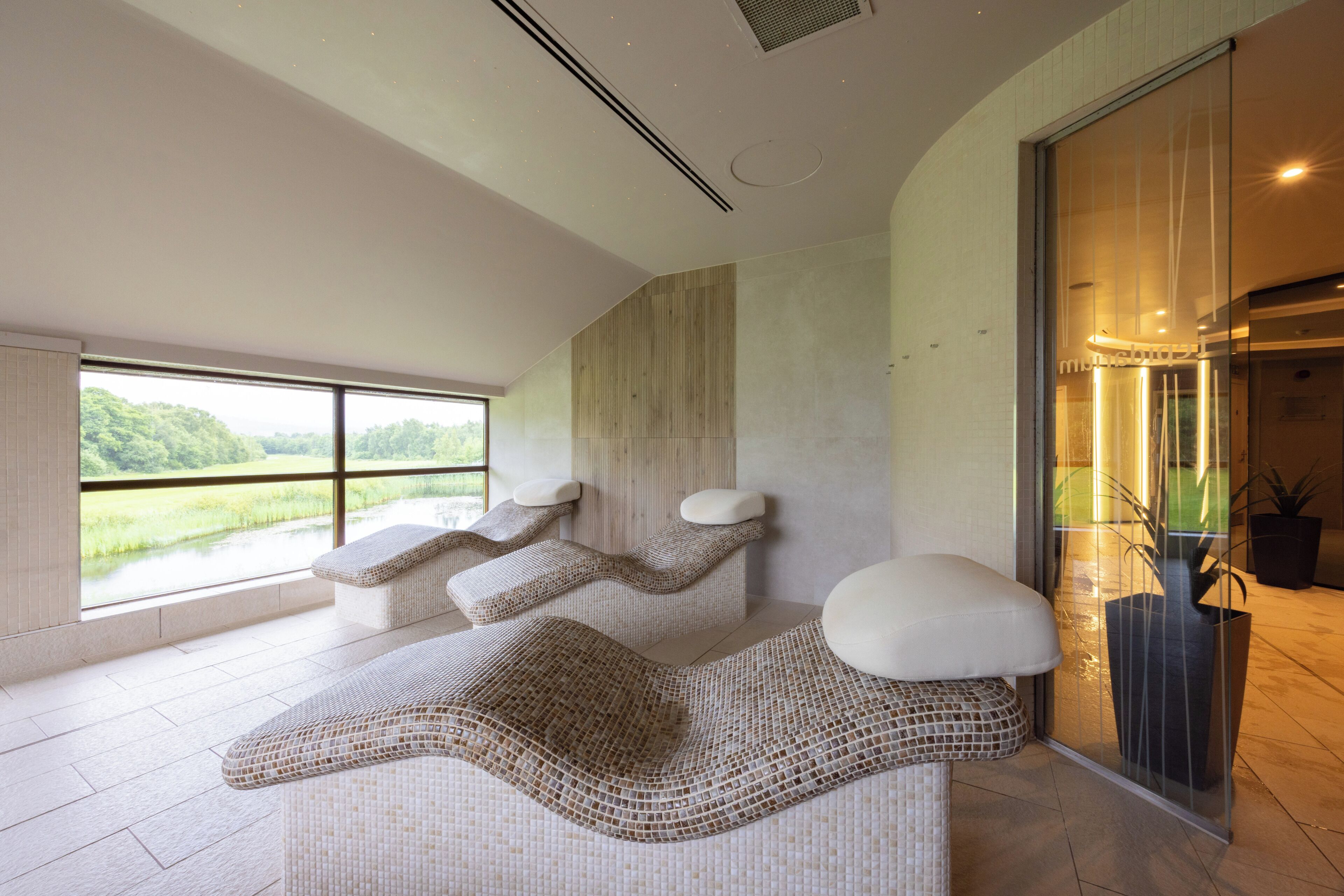 A modern spa area with a large window, a stone wall, and a seating area with a unique woven design.