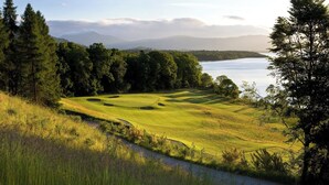 A golf course with a water body and mountains in the background. - Mansion House Apartments at Cameron Lodges (Alexandria)