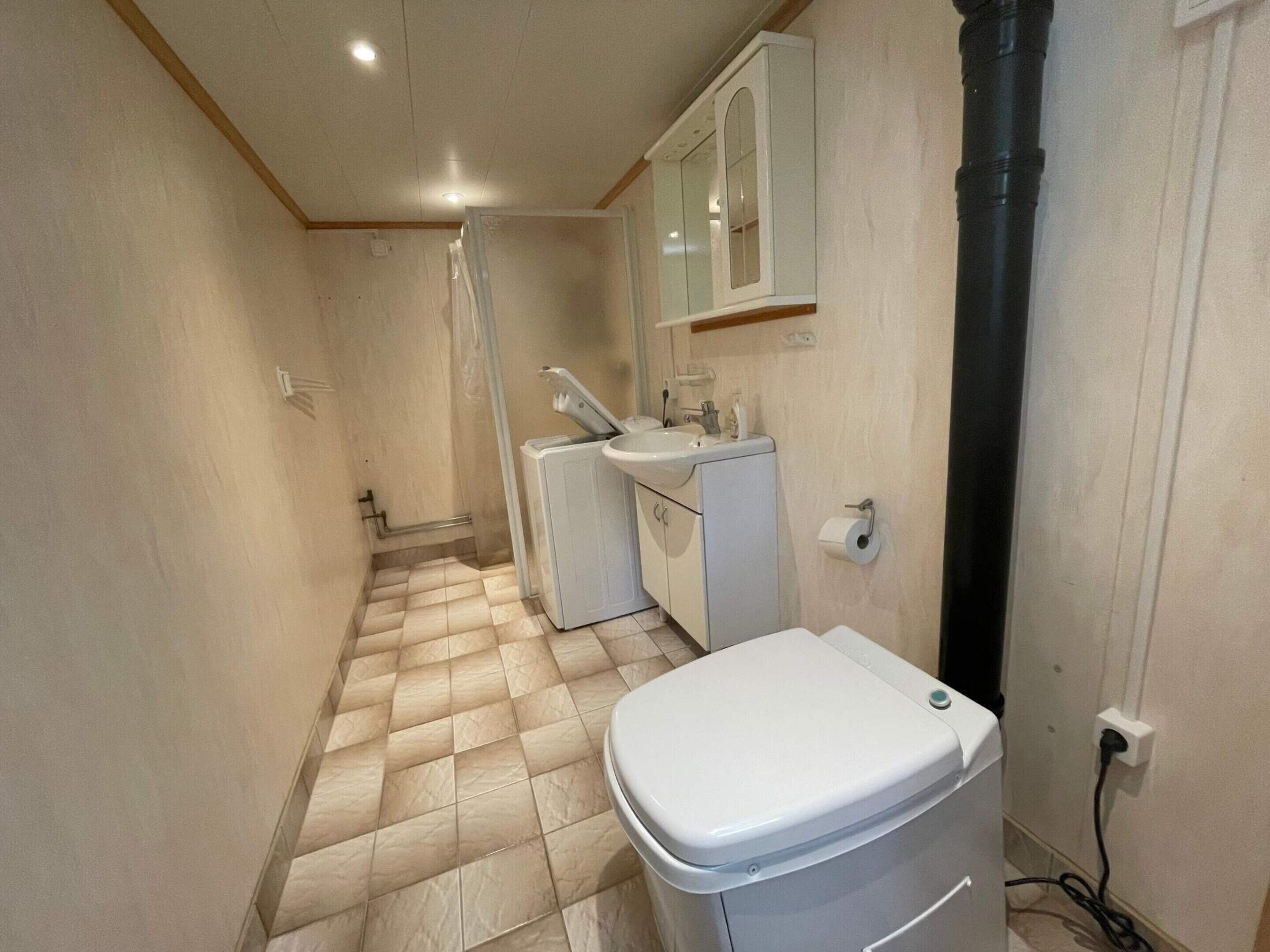 A compact bathroom with a toilet, washing machine, and sink.