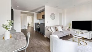 Ein modernes Wohnzimmer mit einem grauen Sofa, einem Esstisch und einem Fernseher.