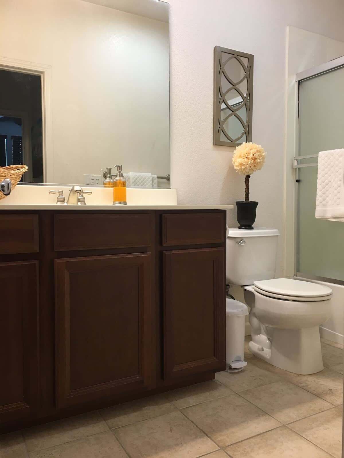 A bathroom with a dark wooden vanity, a white toilet, and a glass shower enclosure.