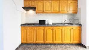 Una cocina con armarios de madera, microondas, tostadora y un lavabo.