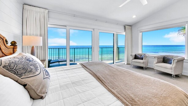 A spacious bedroom with a large bed, a sitting area with two armchairs, and a balcony with a view of the ocean. - Blue Mountain Beach Villas 5A (Santa Rosa Beach)
