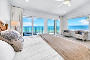 A spacious bedroom with a large bed, a sitting area with two armchairs, and a balcony with a view of the ocean. - Blue Mountain Beach Villas 5A (Santa Rosa Beach)