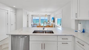 A modern kitchen with white cabinetry, a stainless steel dishwasher, and a large island with a sink. - Blue Mountain Beach Villas 5A (Santa Rosa Beach)