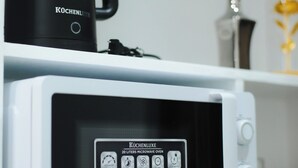 Una cocina con un microondas blanco y una cafetera negra sobre la encimera.