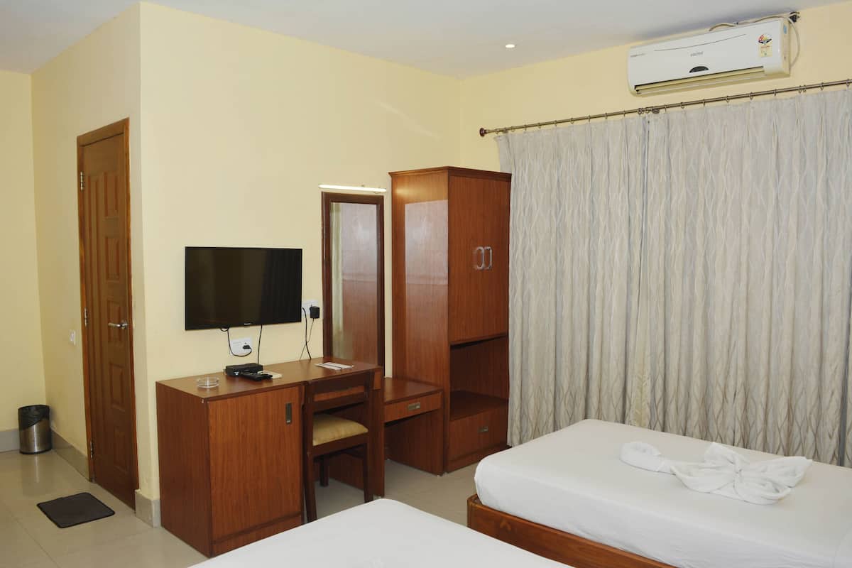 Una habitación de hotel con cama, escritorio, armario, televisor y aire acondicionado.