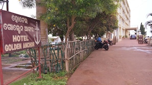 Señal del Hotel Golden Anchor, un edificio con entrada porticada, motocicletas estacionadas y un camino pavimentado.