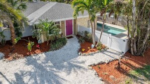 Une maison avec une piscine, entourée de palmiers et dotée d’une allée en gravier.